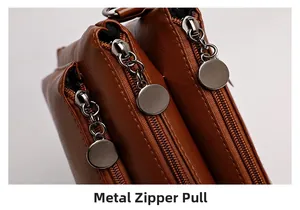 Detail of brown leather handbag featuring three zip compartments and metal zipper pullers