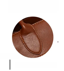 Close-up of reinforced stitching and lychee pattern leather texture on a brown tote bag