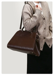 Detail of vintage large tote bag showing bottom metal studs and smooth brown faux leather
