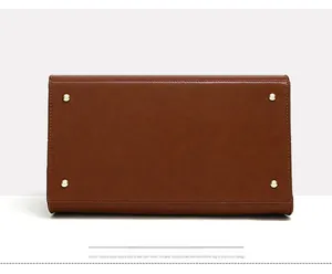 Detailed bottom view of brown leather tote bag with four protective gold metal studs