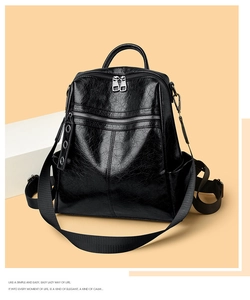 Detail of black glossy leather backpack featuring silver zippers and front hidden pocket