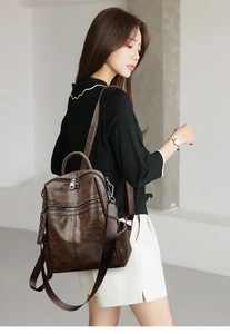 Detail of dark brown vintage leather backpack showing high-quality texture and silver zippers