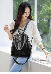 Lifestyle shot of a vintage black PU leather backpack with silver zippers on a model