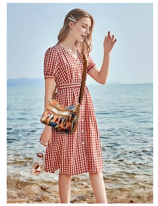 Dettaglio di una borsa a tracolla in pelle patchwork colorata sulla spiaggia con mare