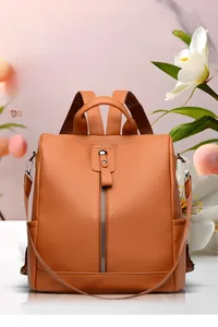 Detail view of orange lychee faux leather backpack with vertical metal zipper and top handle