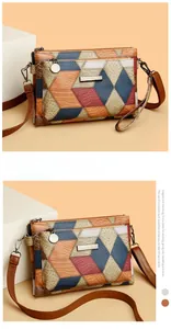 Detail of color-block crossbody bag with lychee grain texture and zipper compartments