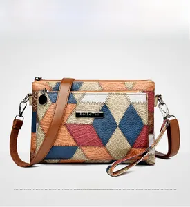 Detail of color-block patchwork handbag with textured leather and golden metal logo