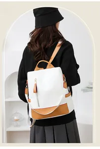 Close-up of white and brown contrast leather backpack showing red edge details on model