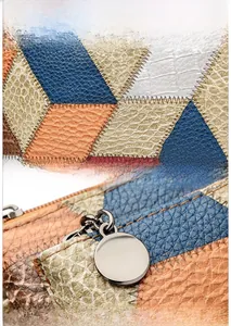 Close-up of color-block geometric pattern stitching and round metal zipper on the handbag