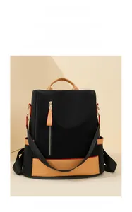 Detail of black nylon backpack with brown leather trim and vertical metal zipper
