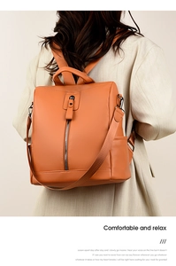 Detail of orange oxford fabric backpack featuring side pockets and leather handle strap