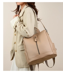 Side view of beige minimalist faux leather backpack worn by a model in a professional blazer