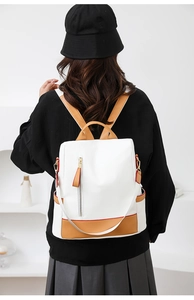 Detail of white lychee leather backpack featuring brown straps and red edge paint detail