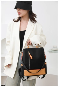 Detail of a black and caramel patchwork backpack showing nylon fabric and leather edging