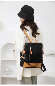 Detailed view of black nylon backpack with yellow contrast stitching and gold zippers