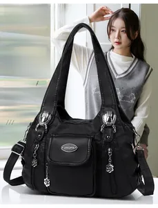 Close-up of black pebbled leather tote bag with silver floral pendant and side zip pockets