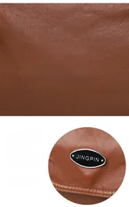 Close-up of brown lychee texture leather shoulder bag with oval silver metal logo plate
