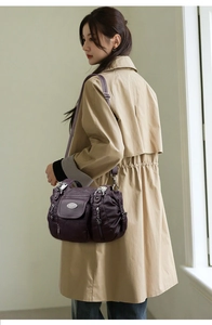 Detail of a dark purple faux leather shoulder bag with multiple functional zip pockets