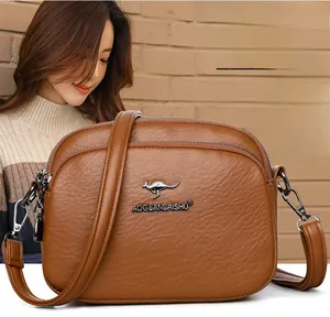 Detail of caramel lychee grain leather crossbody bag featuring adjustable strap and metallic hook