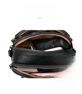 Macro view of multi-compartment black leather bag showing large capacity for essentials