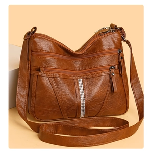 Macro detail of the brown soft PU leather texture and rhinestone accents on the crossbody bag