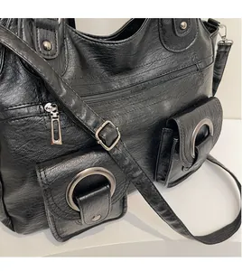 Detail of black faux leather tote featuring silver ring buckles and multi-zipper pockets
