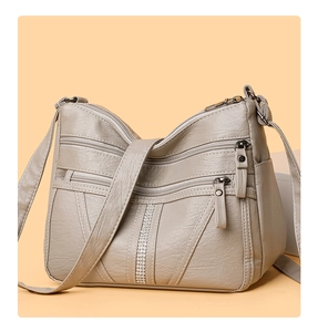 Detail of grey soft leather shoulder bag with multiple zippers and rhinestone stripe