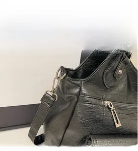 Detailed close-up of glossy black leather handbag with premium silver hardware and zipper