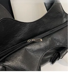 Detailed macro view of the smooth metal zipper and textured black leather bag flap