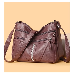 Detail of wine red soft leather shoulder bag with multiple zippers and rhinestone decor