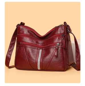 Detail of burgundy PU leather handbag with multiple zipper pockets and rhinestone strip