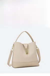 Detail of beige bucket bag with gold lock buckle and smooth leather patchwork design