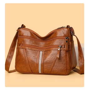 Close-up of brown textured PU leather bag with multiple zippers and rhinestone detail