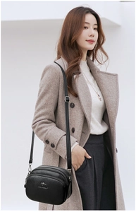 Detail of black crossbody bag with litchi texture and multiple zipper layers