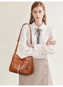Detailed view of brown faux leather shoulder bag with vertical rhinestone trim and zip compartments