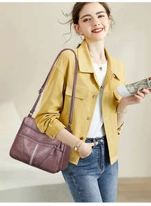 Detail of purple soft leather crossbody bag with rhinestone accents and multi-zipper pockets