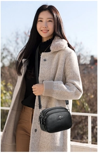 Close-up of black litchi pattern leather crossbody bag with multiple zipper compartments