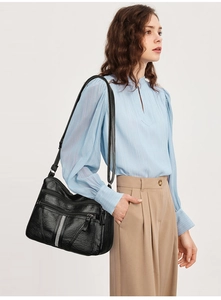 Detail of black leather shoulder bag with multiple zippers and sparkling rhinestone trim