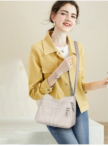 Detail of beige litchi grain faux leather crossbody bag with multiple zipper pockets