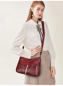 Close-up of wine red lychee leather texture and functional zippers on a large shoulder bag