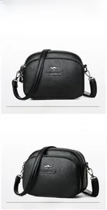 Detail view of black litchi leather texture and kangaroo logo on the crossbody bag