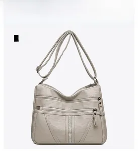 Detail view of light gray faux leather shoulder bag with zipper pockets and rhinestones