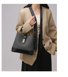 Detail of grey composite texture with black leather trim and gold twist-lock on handbag