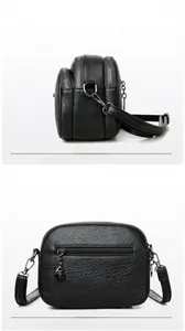 Detail view of the black crossbody bag showing multi-layered zippers and lychee grain texture