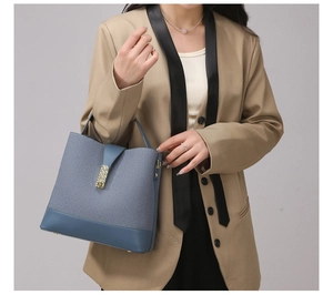 Detail view of navy blue woven bucket bag with smooth leather trim and golden clasp