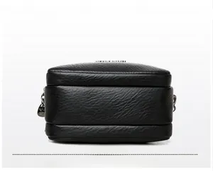 Detailed view of wide base and smooth litchi grain leather texture of black square bag