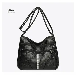 Detail view of large black faux leather shoulder bag with multiple zippers and rhinestones
