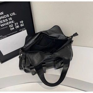 Detail view of large black faux leather tote bag with functional pockets and spacious interior