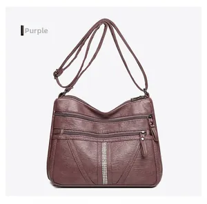 Detail view of purple soft leather crossbody bag with triple zippers and rhinestone trim