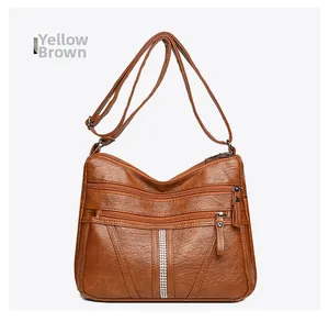 Detail of yellow brown soft faux leather crossbody bag with triple zipper pockets